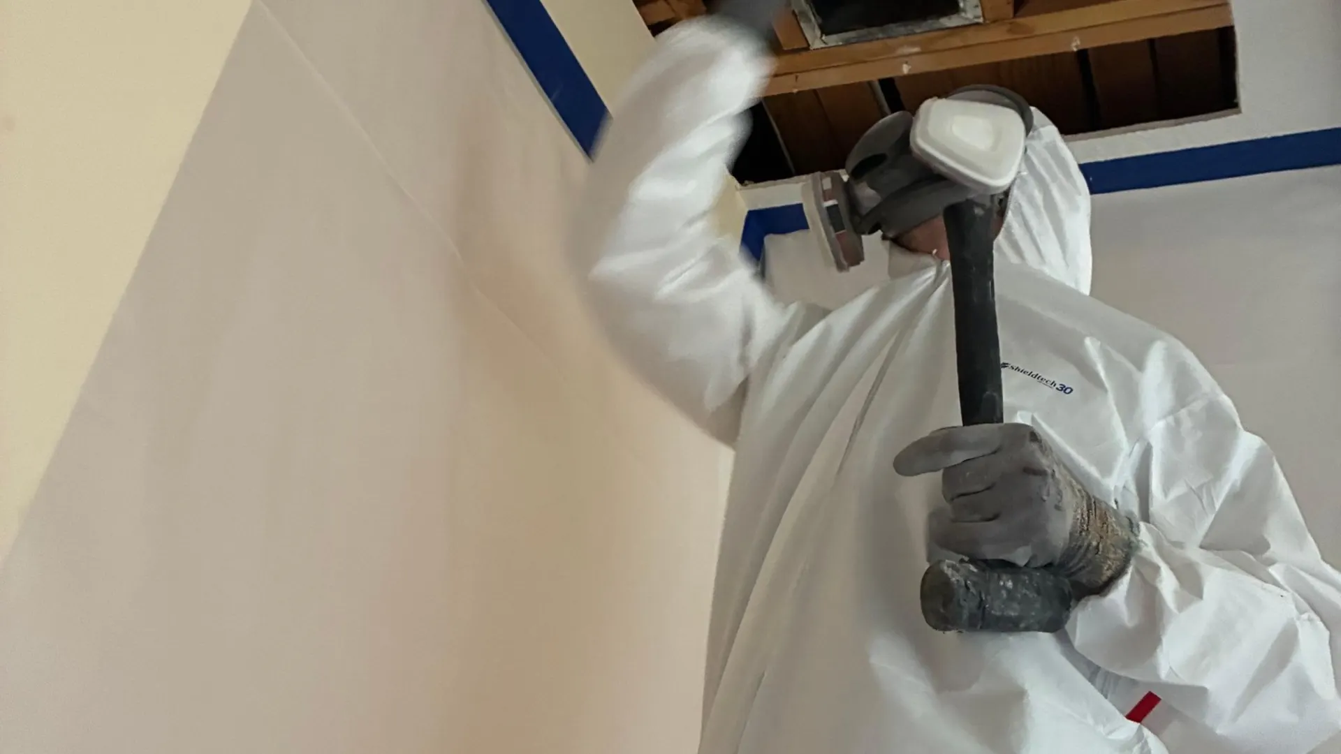 Mold remediation technician opening a ceiling