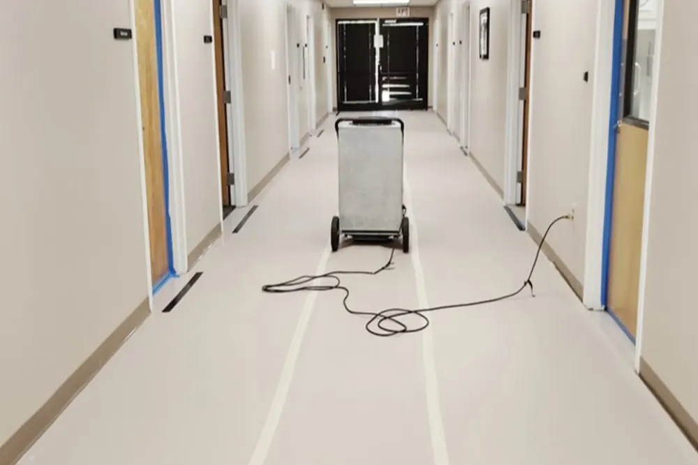 Commercial HEPA air scrubber running in a protected hallway
