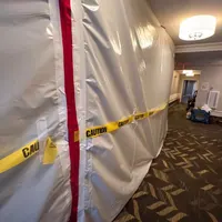 Professional mold containment with zipper door and caution tape in a hallway