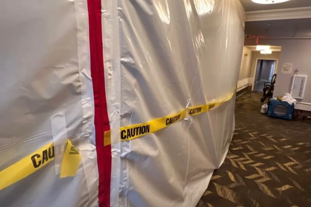 Professional mold containment with zipper door and caution tape in a hallway